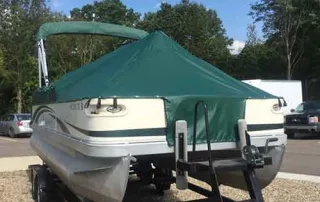 Pontoon boat with green custom cover on trailer